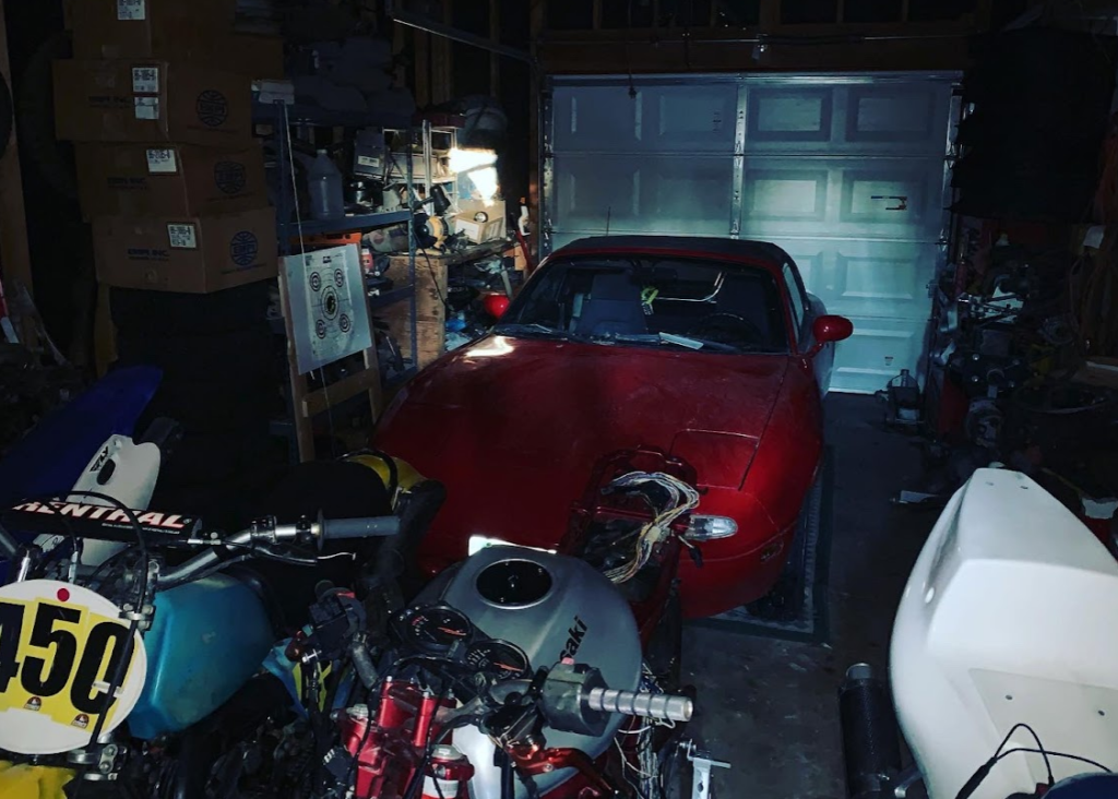 Mazda Miata in the Garage with four bikes parked in front of it