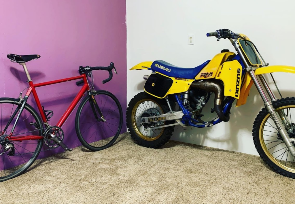 Aston's red road bicycle and yellow and blue 1985 Suzuki RM125