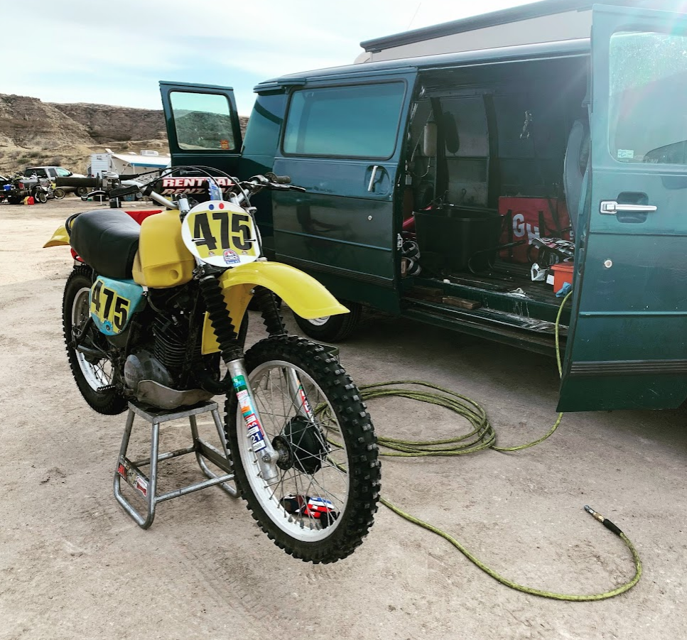 Pic of yellow and blue dirt bike parked next to a green van