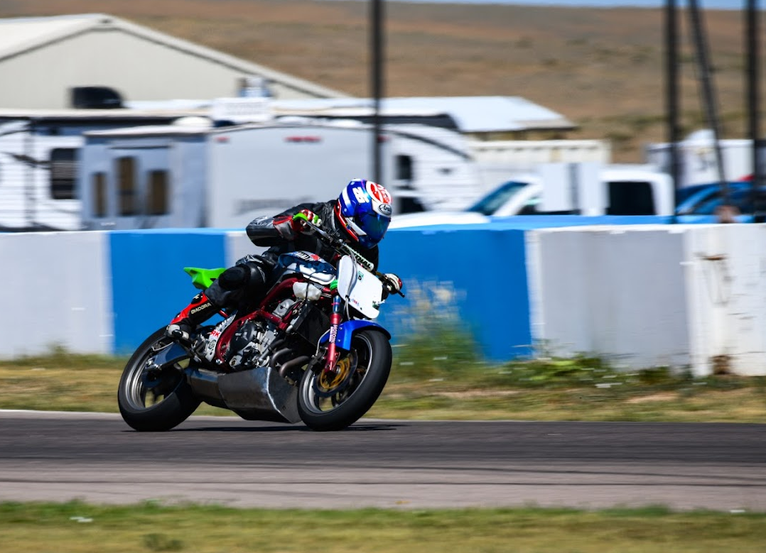 Aston at speed on a Ninja 650 with a blue fender and green tail section entering Turn 1 at High Plains Raceway 