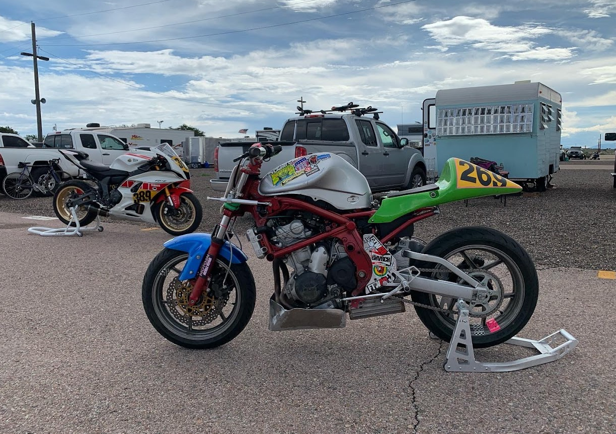 Left side of naked Ninja 650 race bike with red frame, green tail, and blue front fender