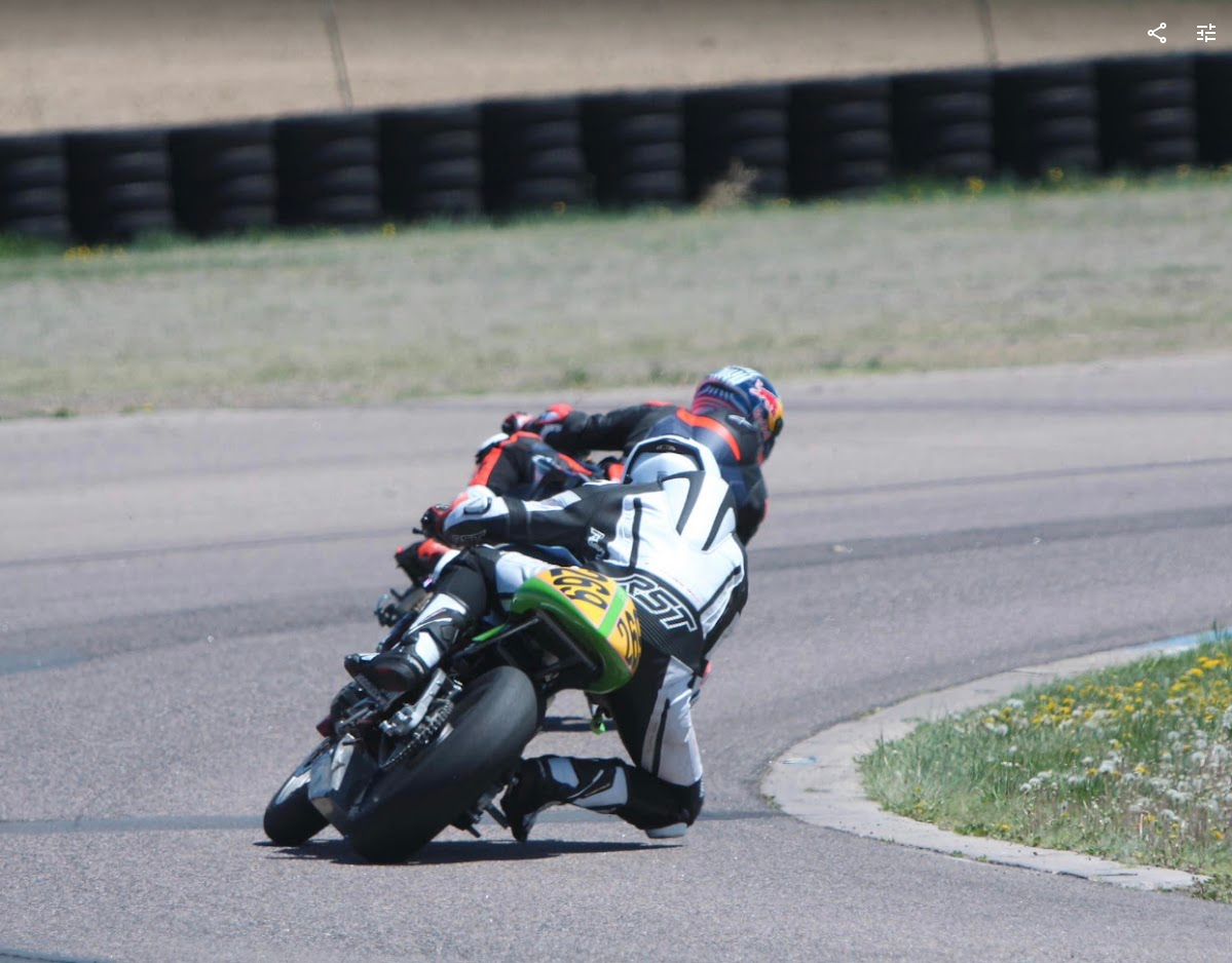 Aston #269 on his beater '06 Kawi ER6 wearing a white and black race suit, bike has a green tain. Knee is about to touch down through Turn 1 at HPR